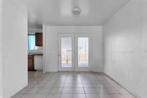 Doorway with baseboards and tile patterned flooring