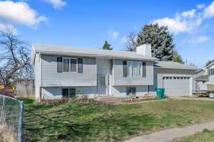 Split foyer home featuring an attached garage, a chimney, and driveway