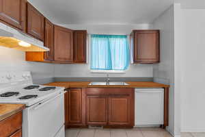 Kitchen featuring white appliances, wood finish cabinets, and light tile patterned floors