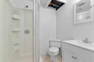 Bathroom featuring a textured wall, a shower stall, vanity, and light tile patterned flooring