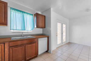 Kitchen featuring dishwasher, wood finish cabinetry, and light tile patterned flooring