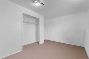 Unfurnished bedroom featuring light colored carpet and a closet