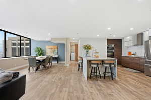 Two tone kitchen with light stone counters, a breakfast bar area, modern cabinets, tasteful backsplash, and light wood-type flooring