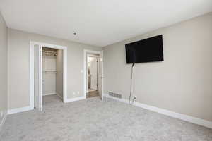 Unfurnished bedroom with a spacious closet and light colored carpet