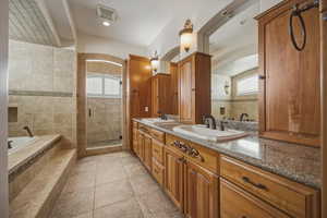 Full bath featuring double vanity, light tile patterned floors, a garden tub, a stall shower, and healthy amount of natural light