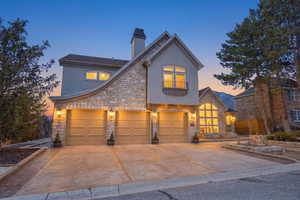 View of front facade featuring stone siding, stucco siding, a chimney, and concrete driveway