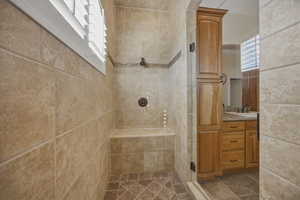 Full bath with vanity, tiled shower, and plenty of natural light