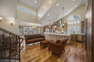 Living area featuring light wood-type flooring, a chandelier, and vaulted ceiling