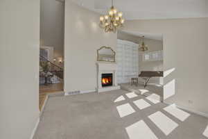 Unfurnished living room featuring light carpet, a warm lit fireplace, vaulted ceiling, and hanging lights