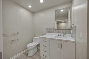 Bathroom featuring vanity, tasteful backsplash, wood tiled floors, and recessed lighting