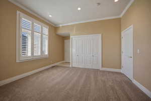 Unfurnished bedroom featuring carpet floors, recessed lighting, crown molding, and a closet
