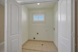 Laundry area featuring hookup for a washing machine, hookup for an electric dryer, and light tile patterned floors