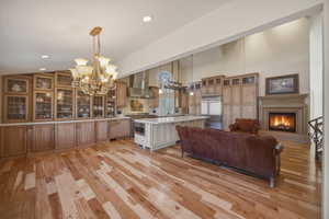 Kitchen with glass insert cabinets, a spacious island, a kitchen breakfast bar, stainless steel appliances, and light wood-style flooring