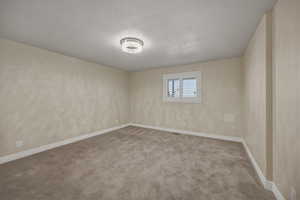 Carpeted empty room with baseboards and a textured ceiling