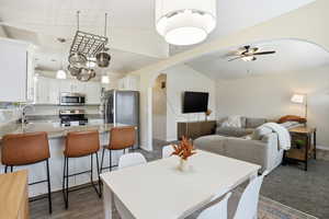 Dining room featuring arched walkways, lofted ceiling, a ceiling fan, and dark wood-style floors