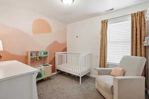 Bedroom with light colored carpet and a nursery area