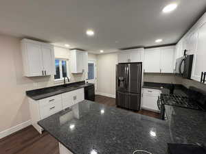 Kitchen featuring dark stone counters, white cabinetry, dark wood finished floors, a peninsula, and recessed lighting