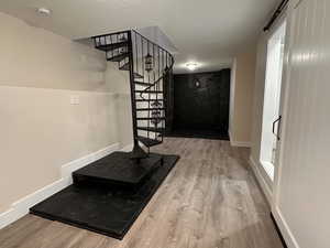 Staircase with a barn door, wood finished floors, and a textured ceiling