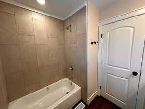 Bathroom with shower / bathtub combination and dark wood-type flooring