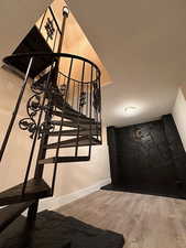 Stairway with wood finished floors and a textured ceiling