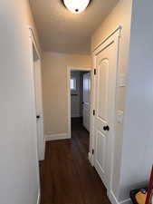 Hall featuring a textured ceiling and dark wood-type flooring