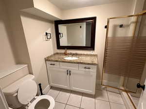 Bathroom featuring vanity, a shower stall, light tile patterned floors, and a textured ceiling