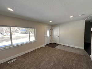 Entryway featuring recessed lighting, dark carpet, and a textured ceiling