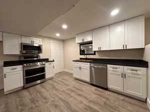 Kitchen featuring stainless steel appliances, white cabinetry, recessed lighting, and light wood-style flooring