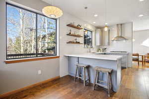 Kitchen featuring gray cabinets, a peninsula, a kitchen bar, and hanging light fixtures