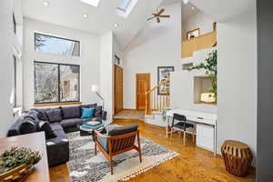 Living area featuring recessed lighting, a skylight, light wood-type flooring, a ceiling fan, and lofted ceiling