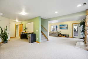 Living room with stairway and light carpet