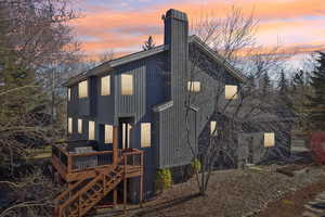 Back of property at dusk featuring a chimney and a deck