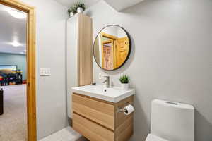 Half bath with vanity, a textured wall, and light carpet