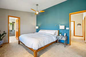 Bedroom with light carpet, ceiling fan, and connected bathroom
