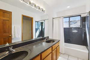 Bathroom with double vanity, light tile patterned floors, and shower / bath combination with curtain