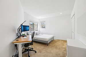 Bedroom with an office area, light colored carpet, recessed lighting, and a closet