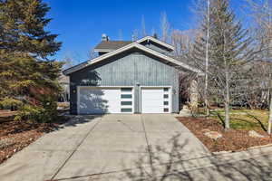 View of front of property featuring a garage, concrete driveway, and a chimney