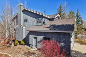 View of side of property with roof with shingles and a chimney