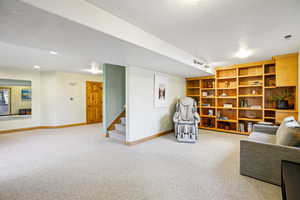 Living area featuring light carpet and a textured ceiling