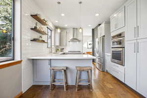 Kitchen with a peninsula, pendant lighting, open shelves, and dark wood-style floors