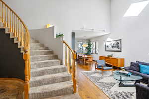 Staircase with wood-type flooring, a high ceiling, and a skylight