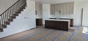 Kitchen with light countertops, a center island with sink, and dual tone cabinetry