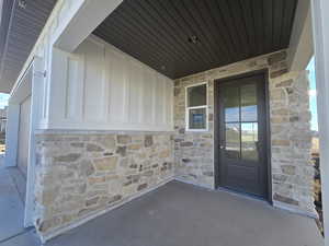 Entrance to property with stone siding, a patio, and board and batten siding