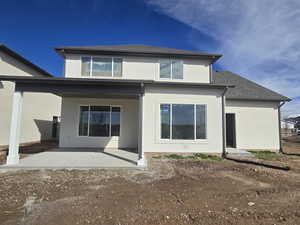 Back of house featuring stucco siding, roof with shingles, and a patio area