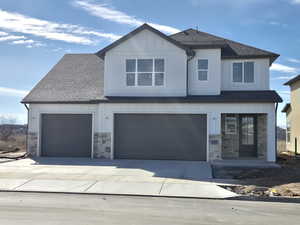 View of front of house featuring board and batten siding, stone siding, concrete driveway, a shingled roof, and an attached garage