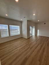 Unfurnished living room with a textured ceiling, recessed lighting, and wood finished floors