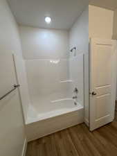Full bath featuring dark wood finished floors,  shower combination, and recessed lighting