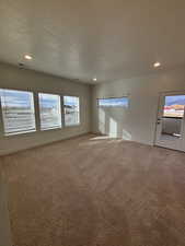 Carpeted empty room with a textured ceiling and recessed lighting