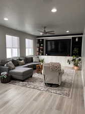 Great Room living area featuring light wood-style flooring, a ceiling fan, custom built cabinetry, and recessed lighting