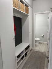Mudroom featuring custom cabinets, light wood finished floors and baseboards